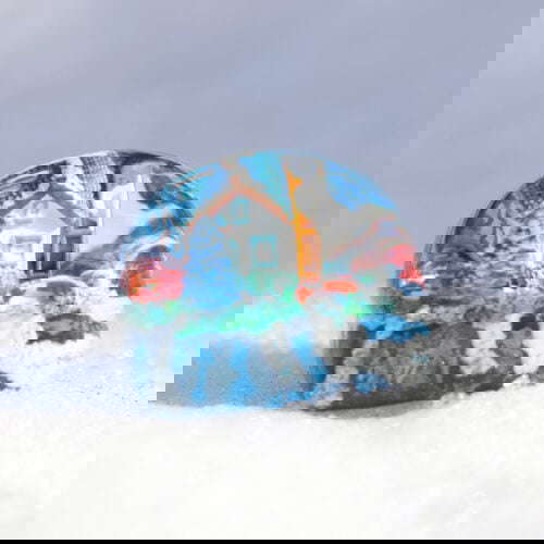 Colorful winter scene inside glass paperweight on snow.
